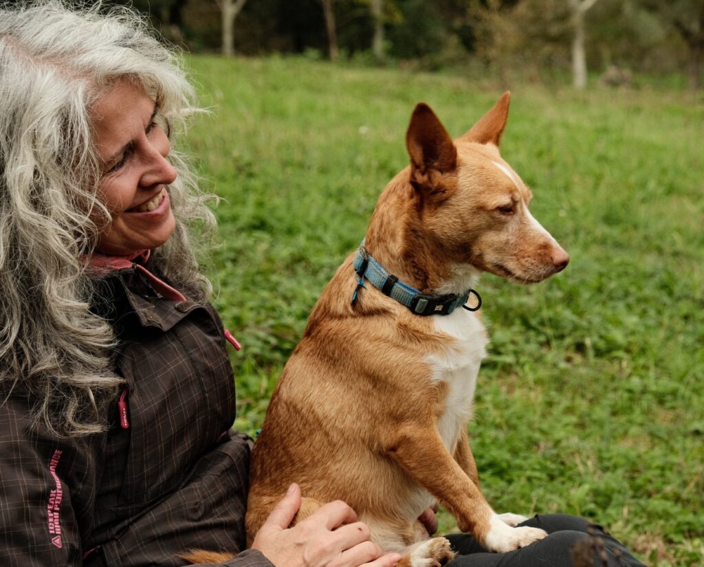 Inicio Foto de Estíbaliz Tello, practicante de los EcoRituales, sonriendo con un perro en sus piernas
